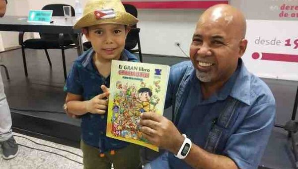 Cuban writer Alexis Diaz (R) shows a children’s book, 2022.