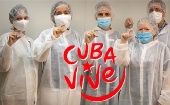 Health professionals show COVID-19 vaccines. The phrase says, "Cuba lives."