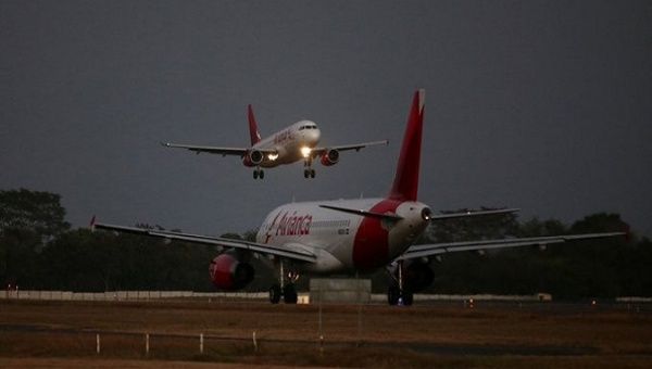 An Avianca Airlines plane lands while another prepares to take off at San Oscar Arnulfo Romero International Airport, San Luis Talpa, El Salvador, Feb. 8, 2022.
