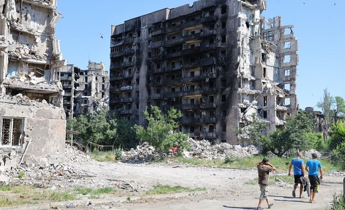 Residents walk past damaged buildings in Mariupol, Ukraine, June 18, 2022.