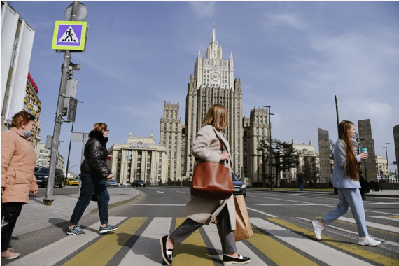 People cross the road in front of the Ministry of Foreign Affairs of Russia in Moscow, on April 16, 2021.