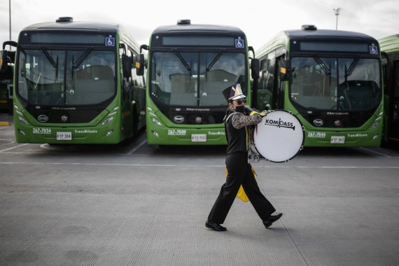 A musician walks past a fleet of electric buses during an event at the Green Mobile Logistics Center in the city of Bogota, Colombia, on March 30, 2022.