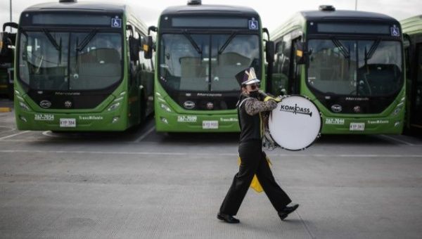 A musician walks past a fleet of electric buses during an event at the Green Mobile Logistics Center in the city of Bogota, Colombia, on March 30, 2022.