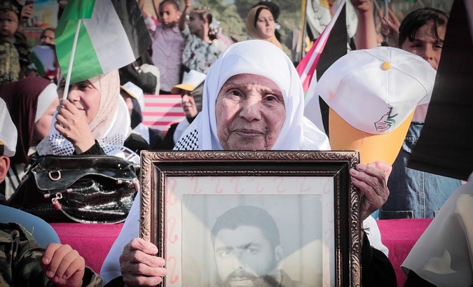 Woman holds portrait of a Palestinian victim of Israeli terrorism.