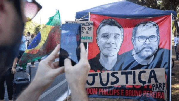 Images of Dom Phillips (L) and Bruno Araujo (R). The sign reads, 