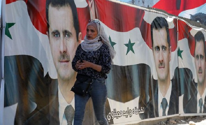 Woman walk past billboards depicting Bashar al-Assad, Damascus, Syria, May 25, 2021.