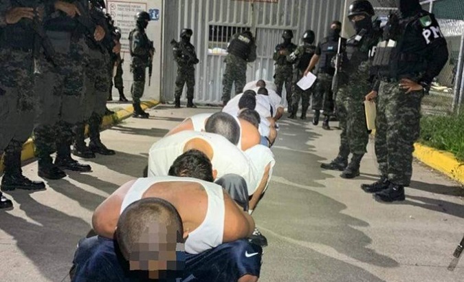 Prisoners squat while being watched by Police, Honduras, July 2023.