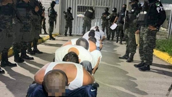 Prisoners squat while being watched by Police, Honduras, July 2023.