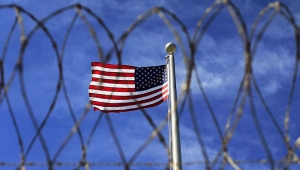 The U.S. flag behind a wired fence, Guantanamo, 2023.