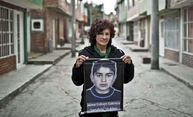 Colombian woman holds the photo of her missing son.