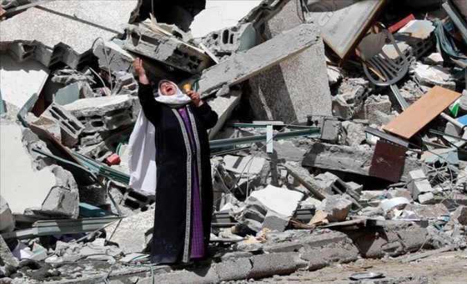 Palestinian woman stands in front of the rubble left by the Israeli bombing, Oct. 7, 2023.