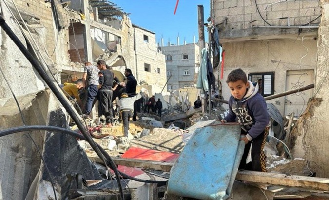 Palestinian boy collects a blanket from the rubble caused by Israeli bombings, Gaza, Feb. 22, 2024.