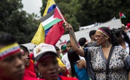 A woman waves the flags of Palestine and Venezuela.